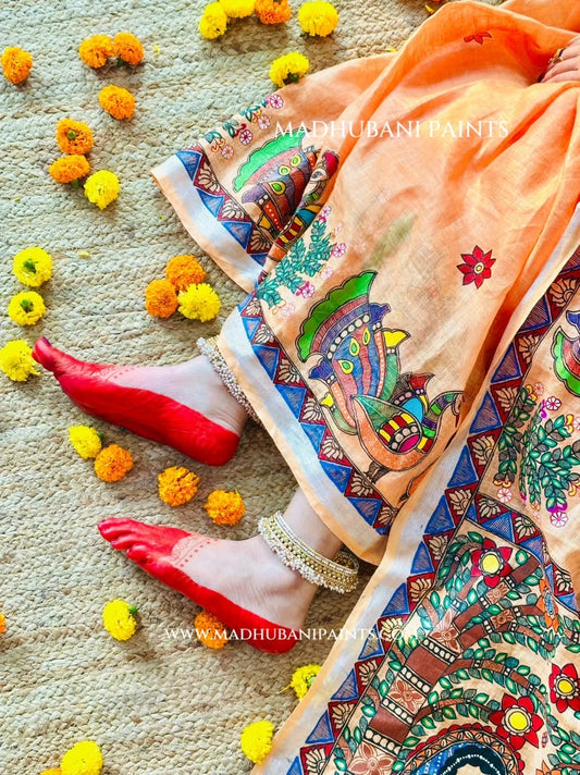Detailed view of peach Madhubani linen saree pleats featuring hand-painted peacock motifs and Radha Krishna artwork on the aanchal.