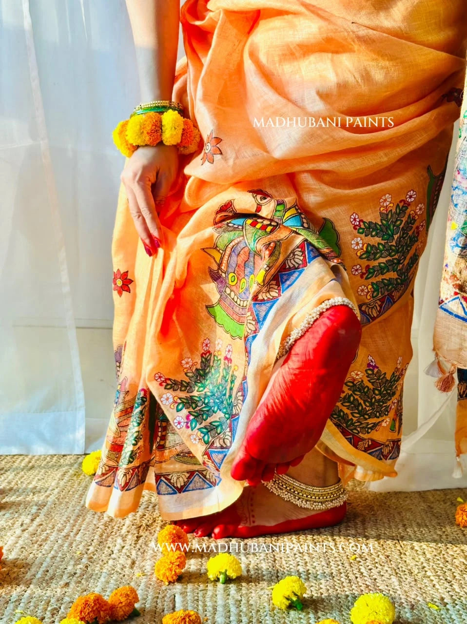 Close-up of peach hand-painted Madhubani linen saree featuring colourful peacock motifs, floral patterns and intricate traditional borders.