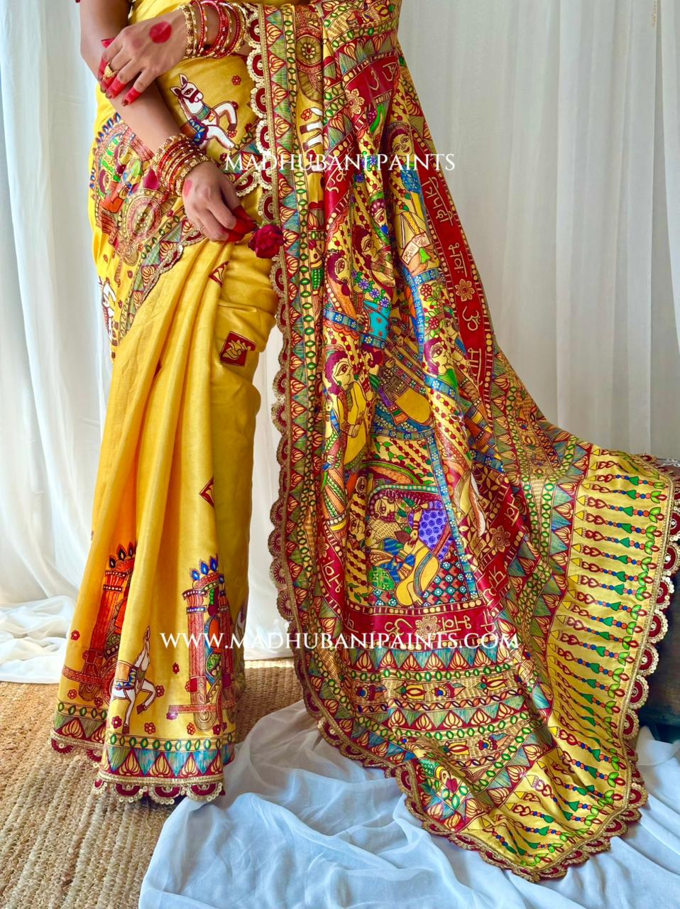 A woman models a vibrant yellow bridal saree with an elaborate multicolor hand-painted border