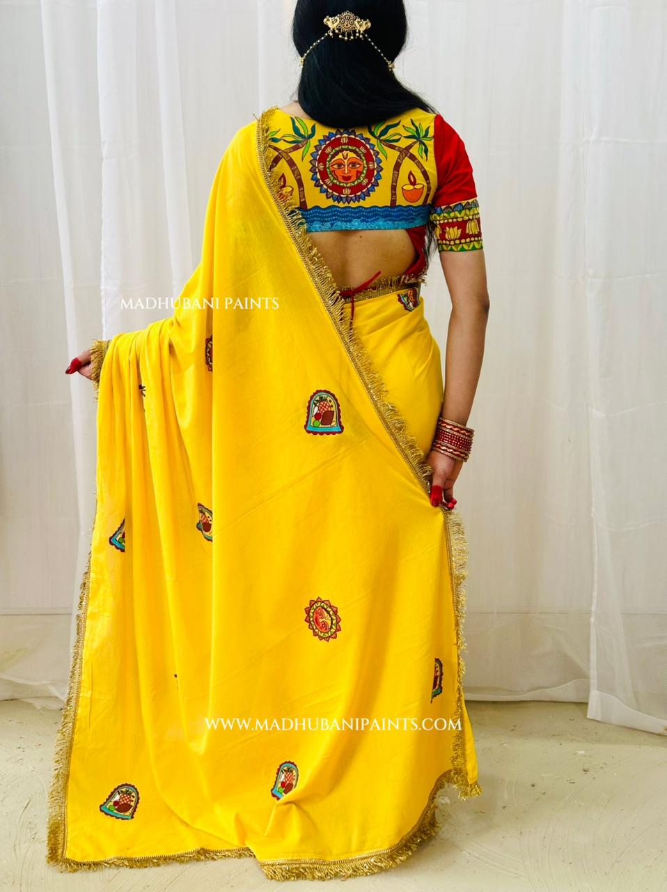 A woman shown from the back wearing a bright yellow chhath puja saree with a heavily madhubani painting red, blue, and gold blouse. 