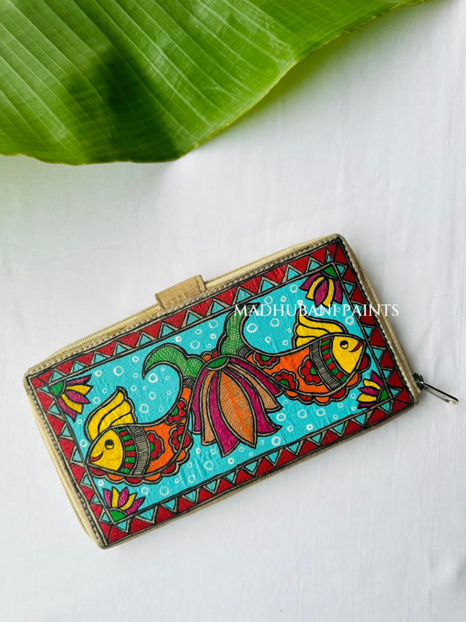 Back Side Of Hand-painted Madhubani clutch in turquoise with two orange-and-yellow fish swimming apart, a lotus flower on the tab closure, and a red triangle border along the base