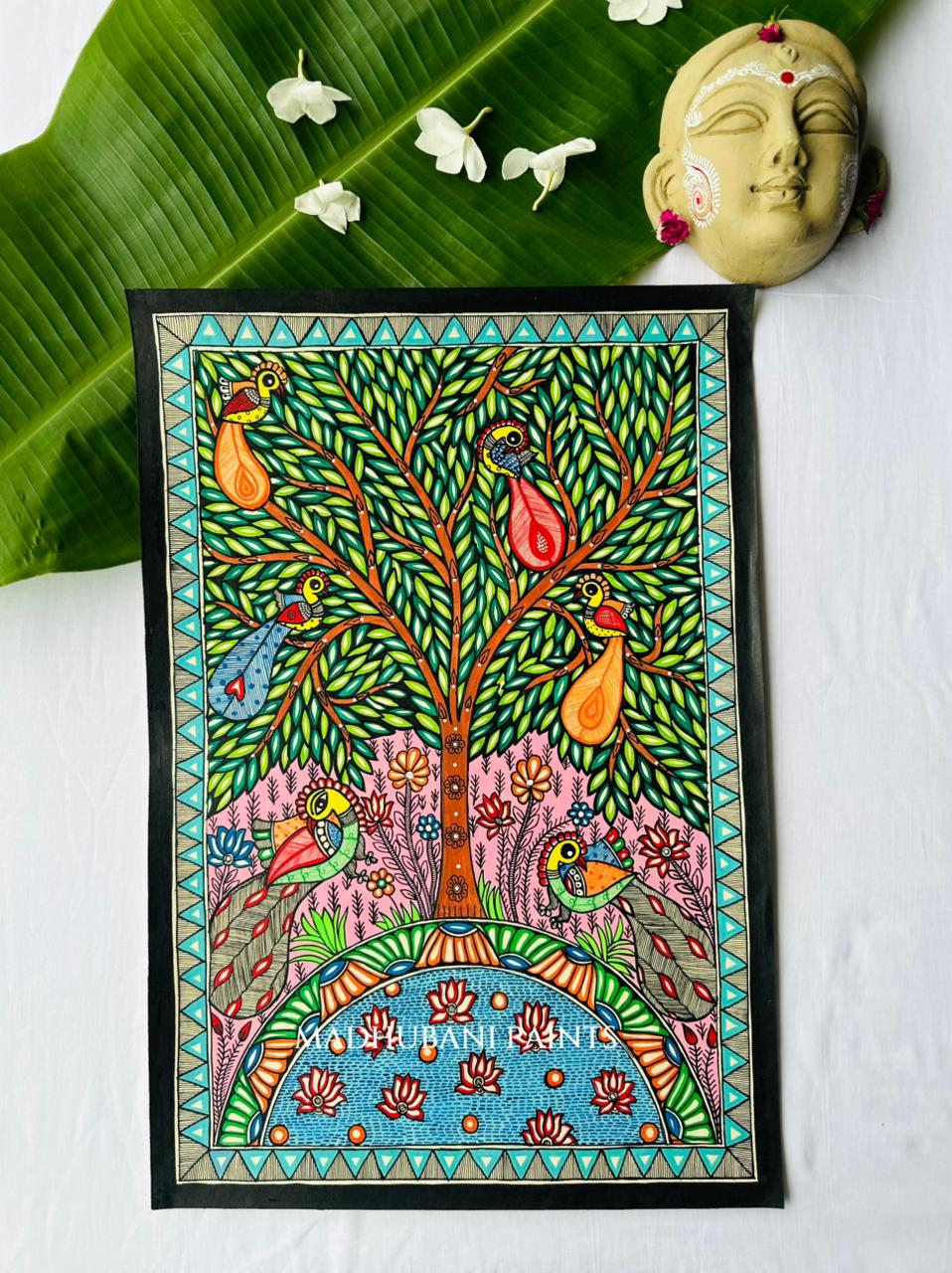 Colorful Madhubani tree of life painting with four birds perched among green leaves, a pink ground, and a semicircular blue lotus pond at the base