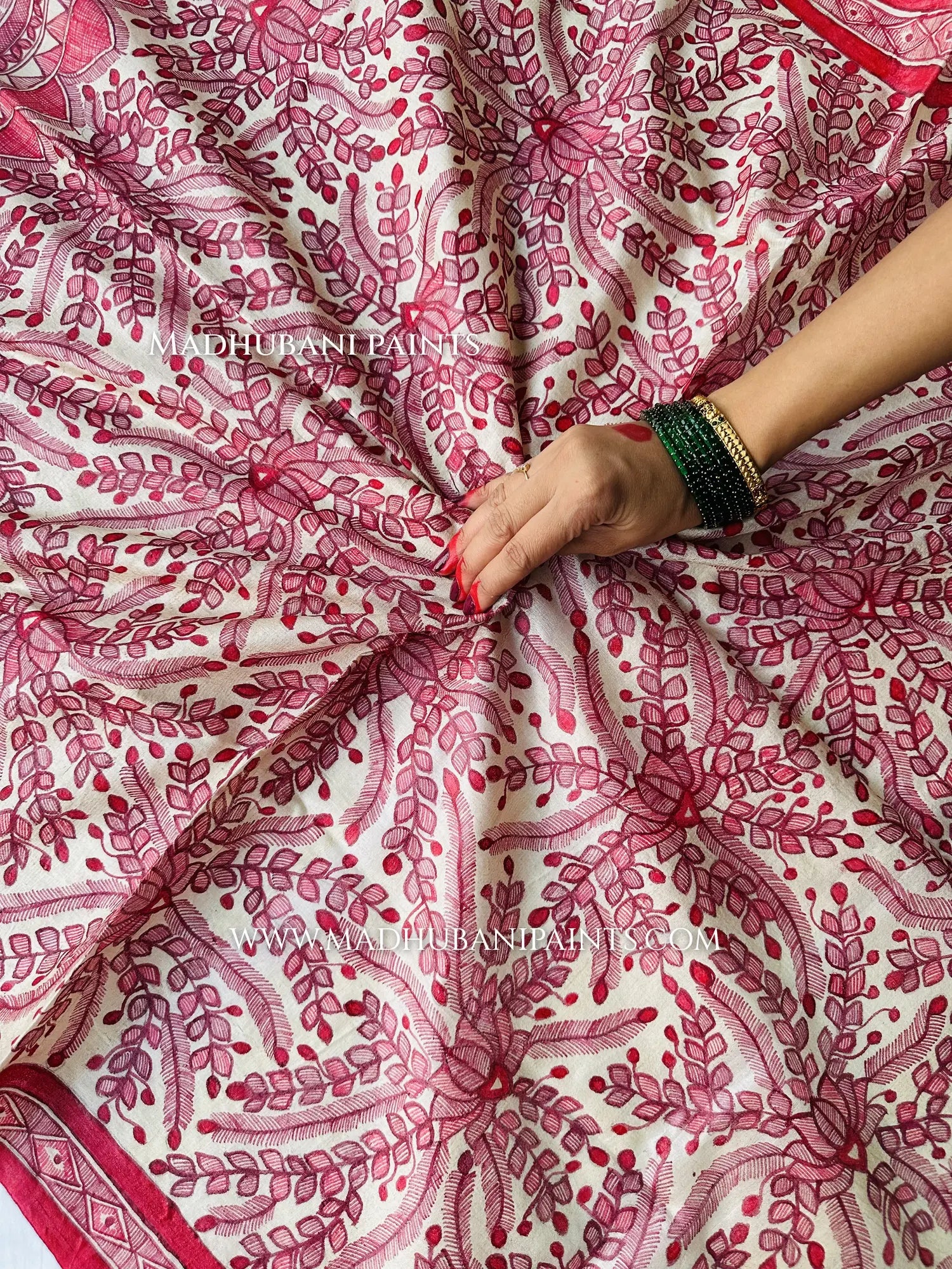 Close-up of a Madhubani hand-painted dupatta with a red border, detailed fish and floral patterns, and a fringed edge.