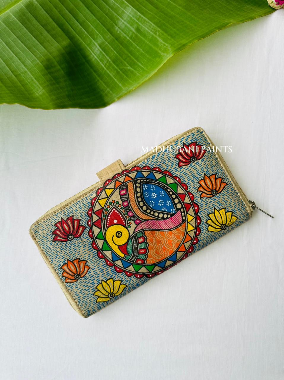 Hand-painted Madhubani clutch with a colorful fish and peacock abordered by triangles, set on a blue dotted background with small lotus flowers