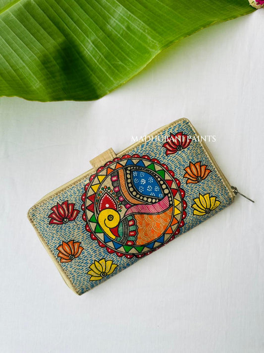 Hand-painted Madhubani clutch with a colorful fish and peacock abordered by triangles, set on a blue dotted background with small lotus flowers