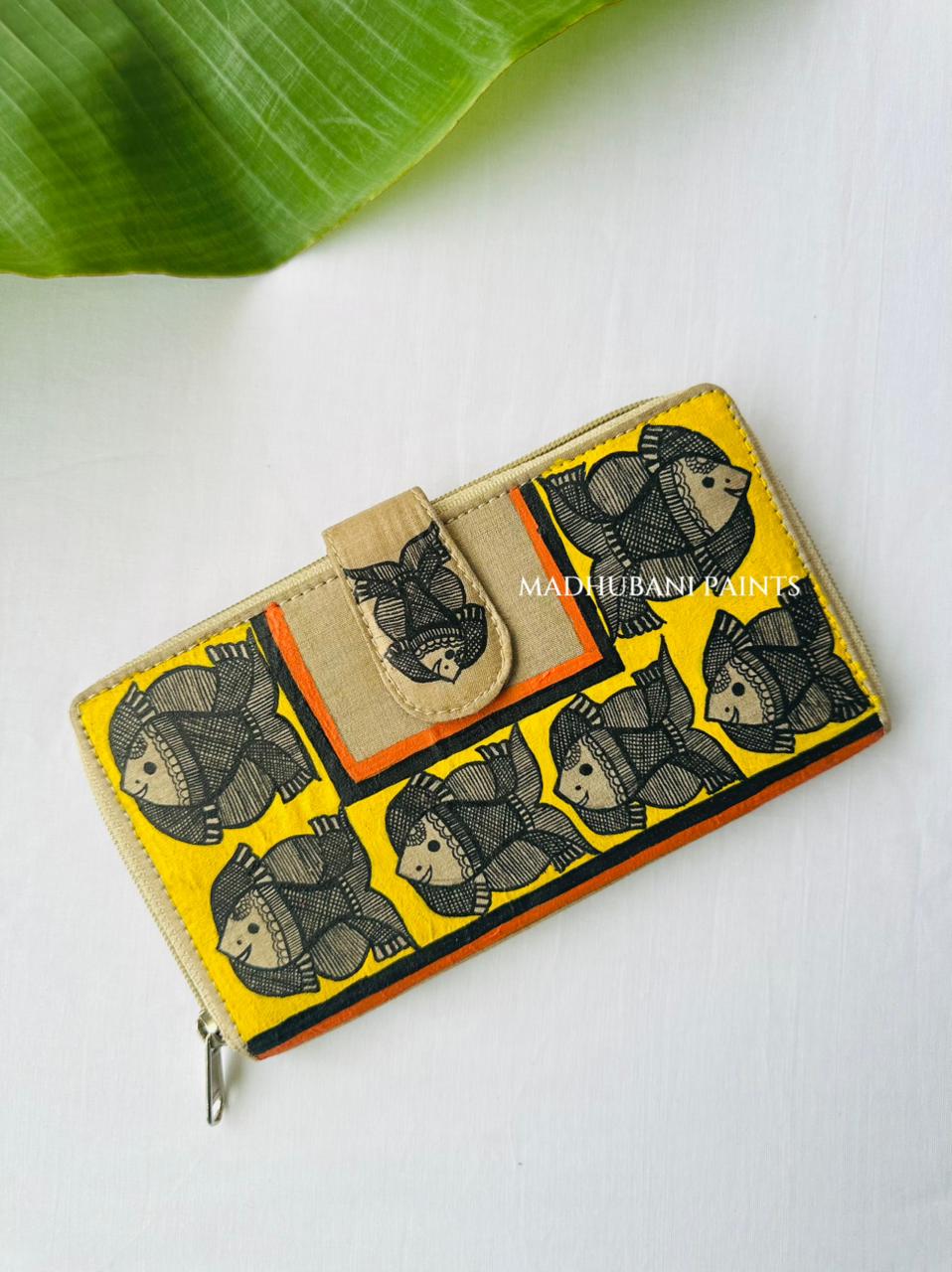 Hand-painted Madhubani clutch with horizontal orange and yellow bands of black-and-cream fish, bordered by a flowering branch motif
