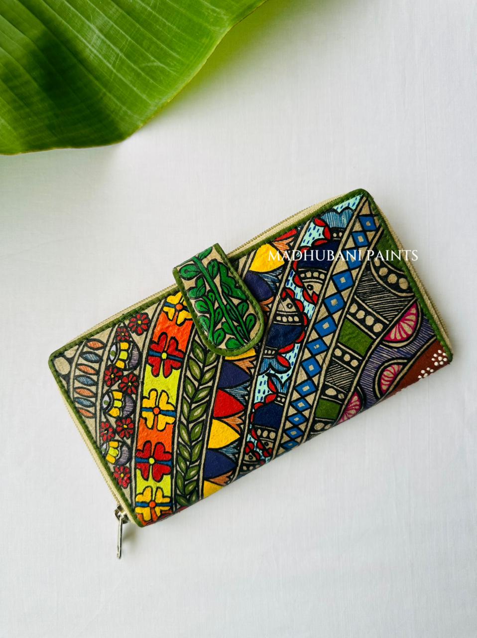 A colorful zip-around wallet decorated with intricate hand-painted tribal patterns in green, yellow, red, blue color