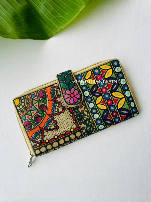 Hand-painted Madhubani clutch with an orange floral mandala on one half and colorful vertical stripes of petals and circles in blue, yellow, and mint on the other, a teal flower on the tab closure