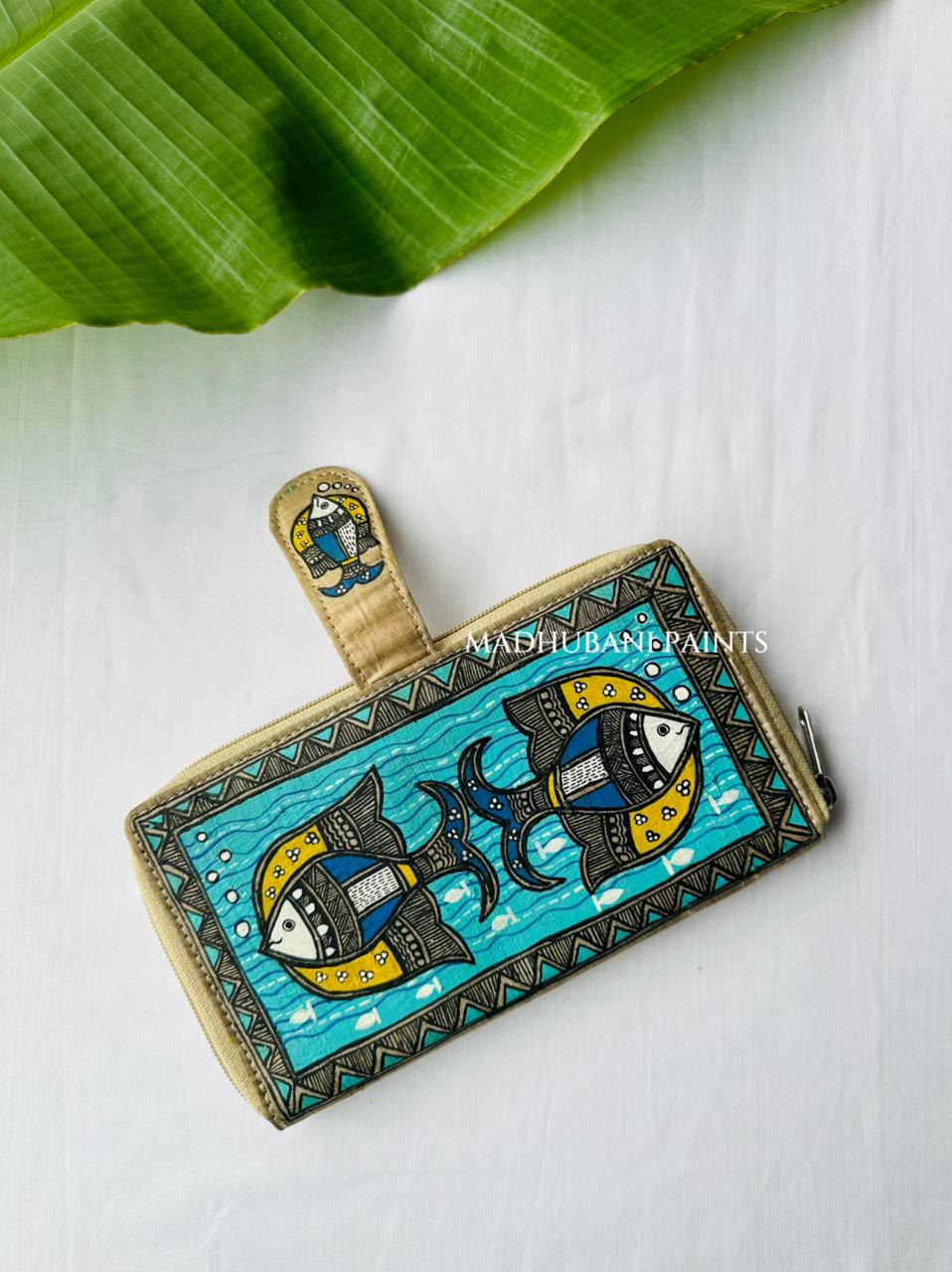 Back side of Hand-painted Madhubani clutch in teal with two fish facing each other over a wave pattern, a small fish painted on the tab closure, and a triangle-and-dot border