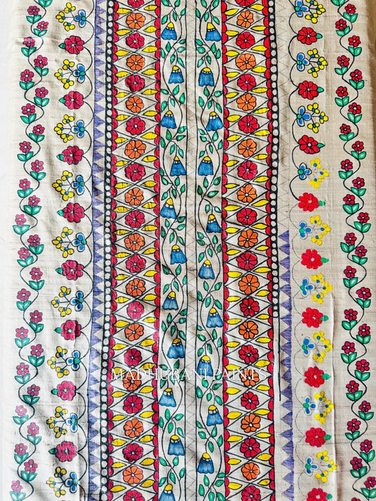 A close-up of a cream-colored fabric with vertical hand-painted floral and nature motif in bright red, pink, orange, yellow, blue, green, and purple.