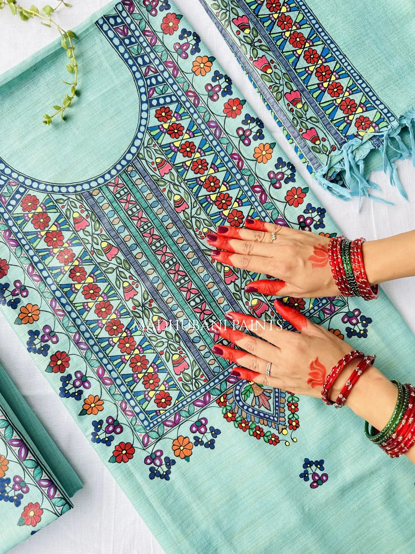 A mint green unstitched salwar suit set with intricate multicolor floral madhubani painting