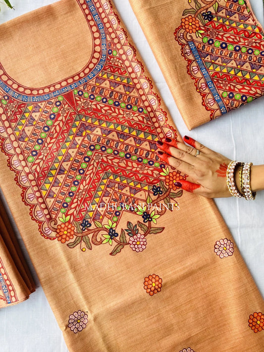 A peach-colored cotton fabric set with intricate multicolor madhubani motif and floral artwork.
