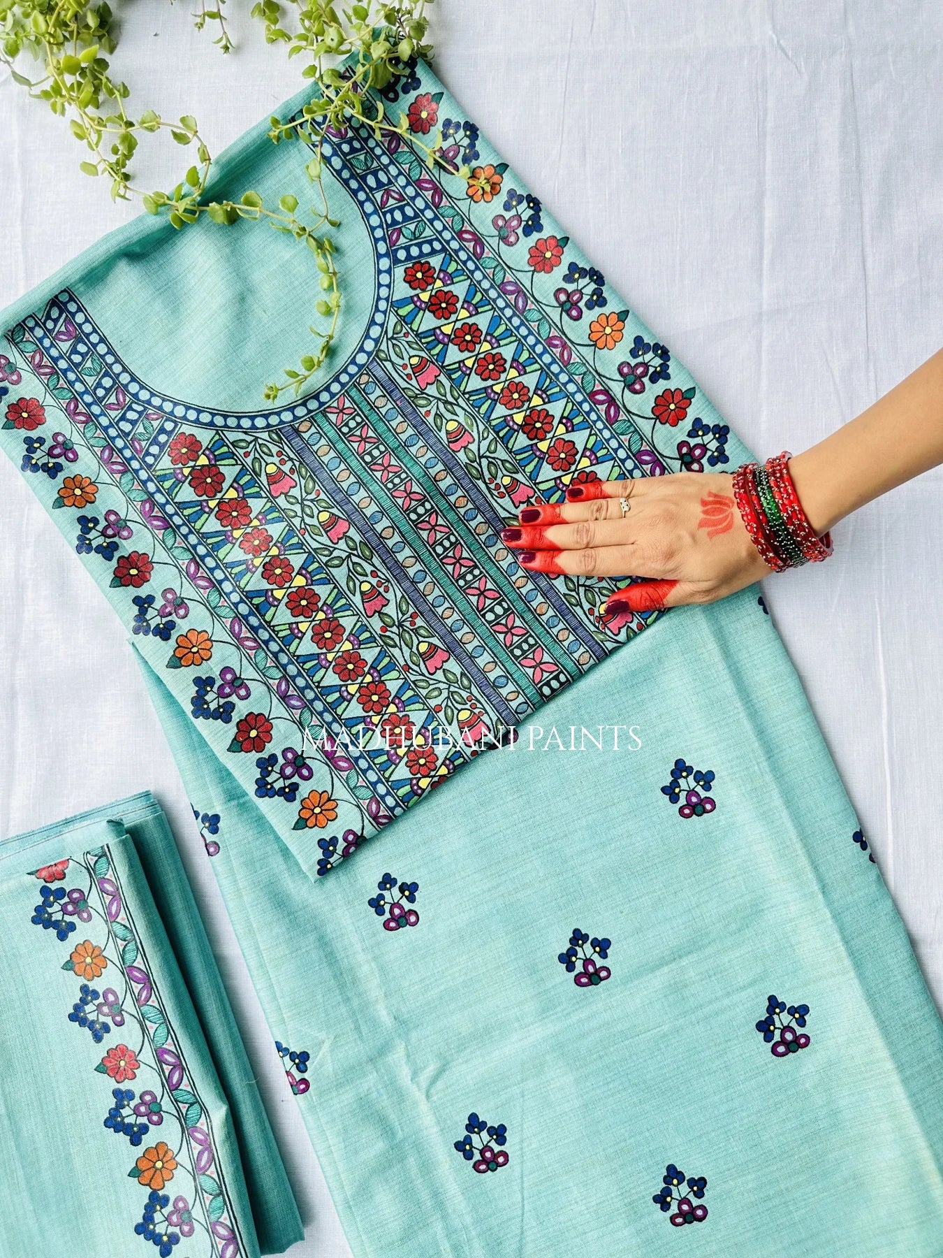 A mint green ethnic salwar suit set, featuring a heavily handpainted neckline with floral motifs on the fabric. 