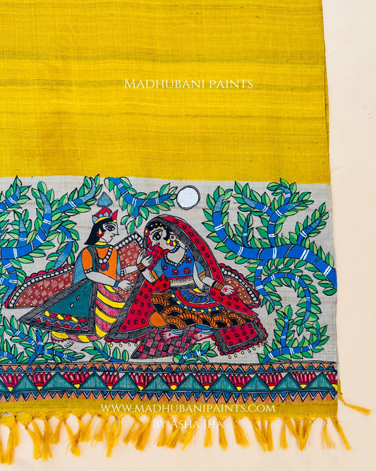 A yellow handloom tussar silk stole with a traditional Madhubani painting depicting Radha and Krishna surrounded by floral patterns.