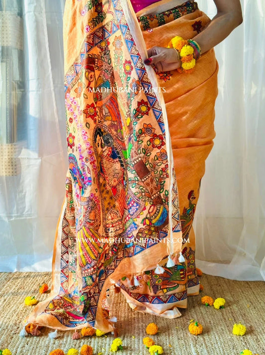 Model wearing a peach linen Madhubani saree with hand-painted peacock motifs, floral borders and traditional Mithila artwork.