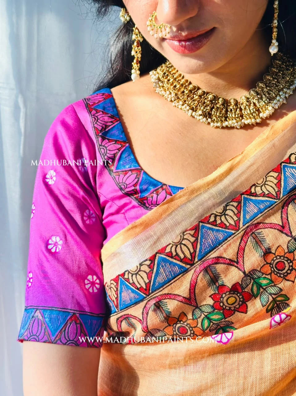 Peach Madhubani painting linen saree styled with a pink blouse, featuring hand-painted peacock designs and colourful floral borders.
