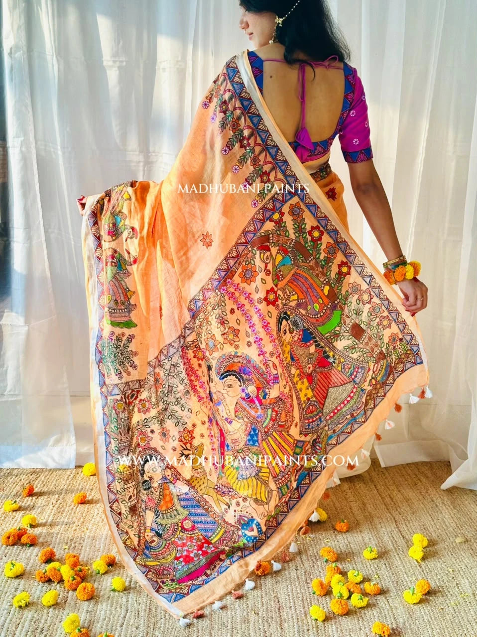 Detailed view of peach linen saree with hand-painted Radha Krishna artwork on the aanchal, peacock motifs and traditional Madhubani borders.
