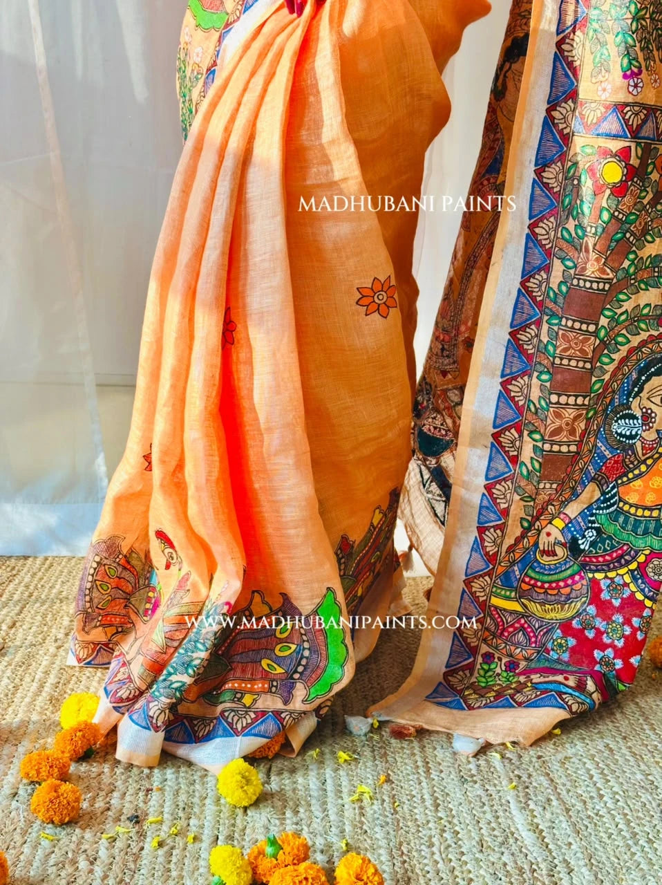 Peach Madhubani linen saree featuring colourful hand-painted peacock motifs, floral designs and intricate Mithila painting borders.