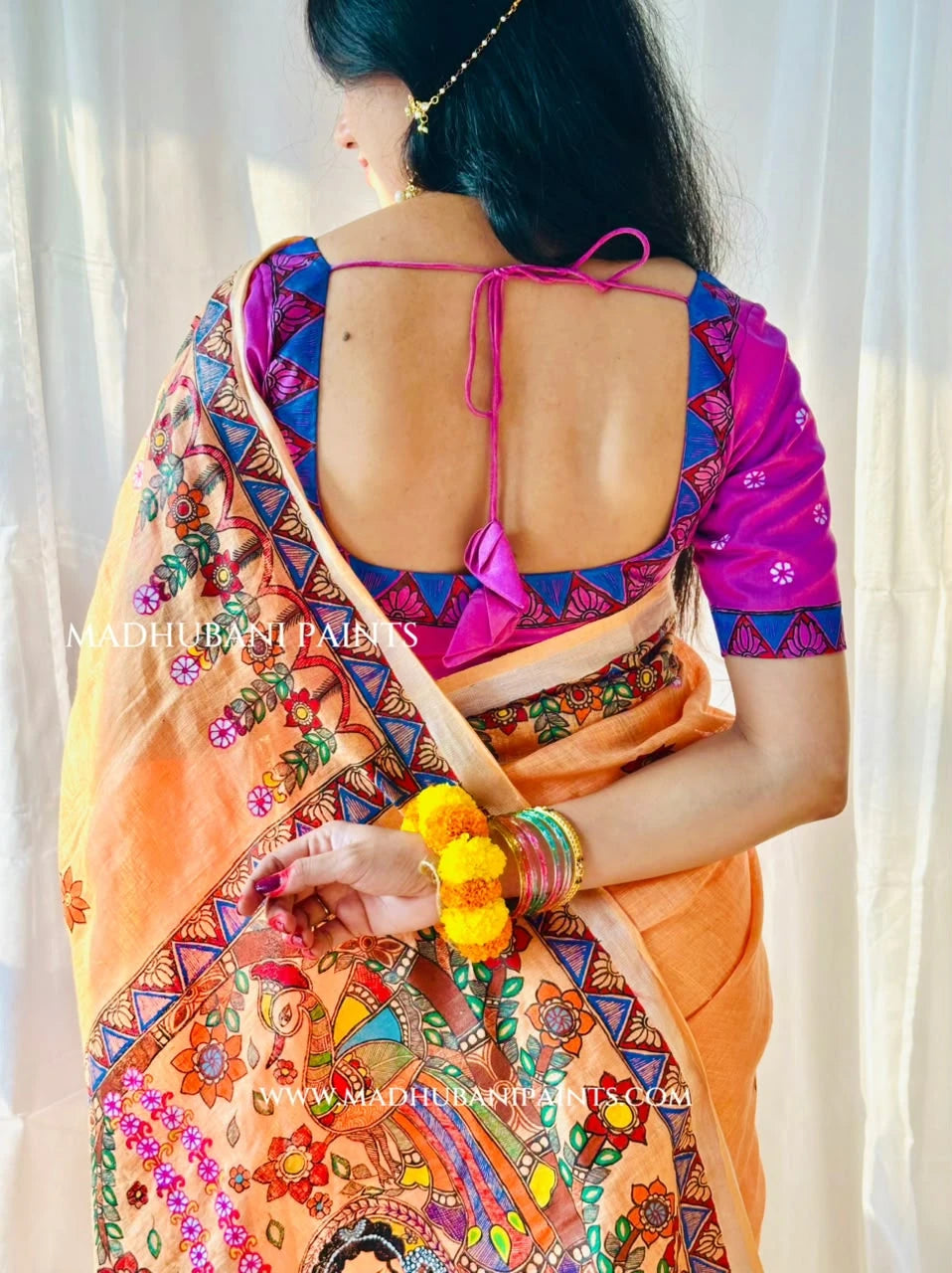 Close-up of pink Madhubani blouse paired with peach linen saree, showcasing hand-painted floral patterns and traditional Mithila borders.