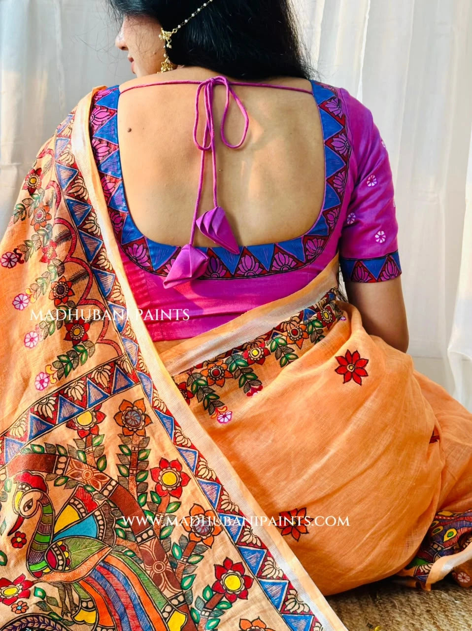 Close-up of peach linen Madhubani saree showcasing hand-painted peacock motifs, floral artwork and detailed traditional borders.
