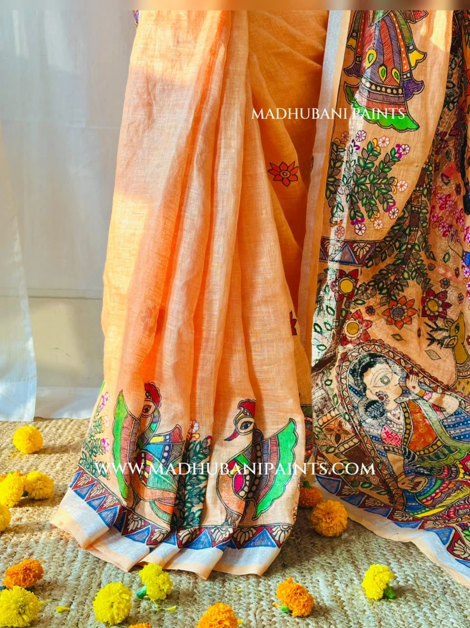Back view of pink hand-painted Madhubani blouse paired with peach linen saree featuring peacock motifs and intricate floral borders.