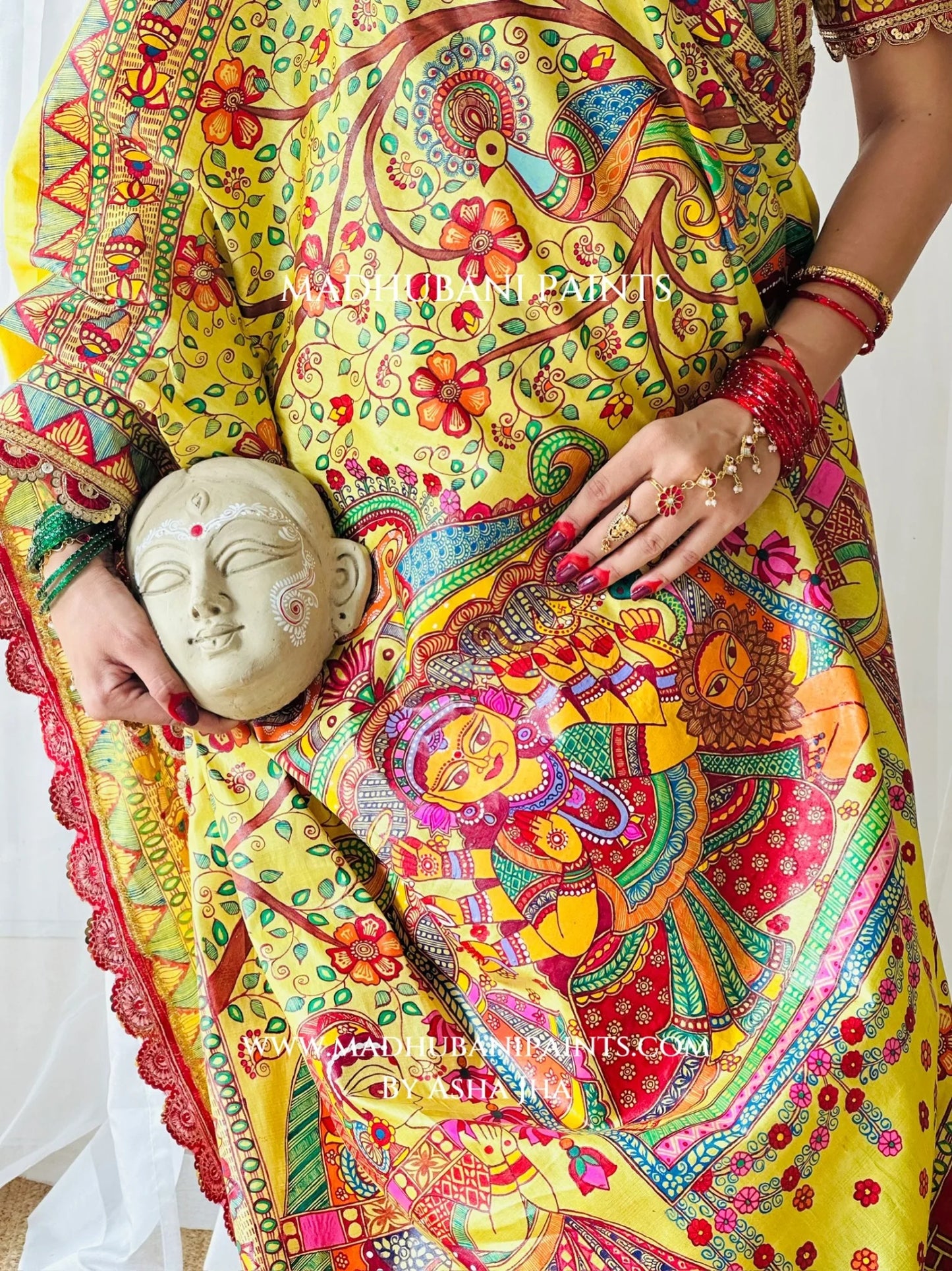 Close-up of Devi Ki Sawari yellow Madhubani saree featuring intricate hand-painted floral motifs, peacock and festive red blouse.