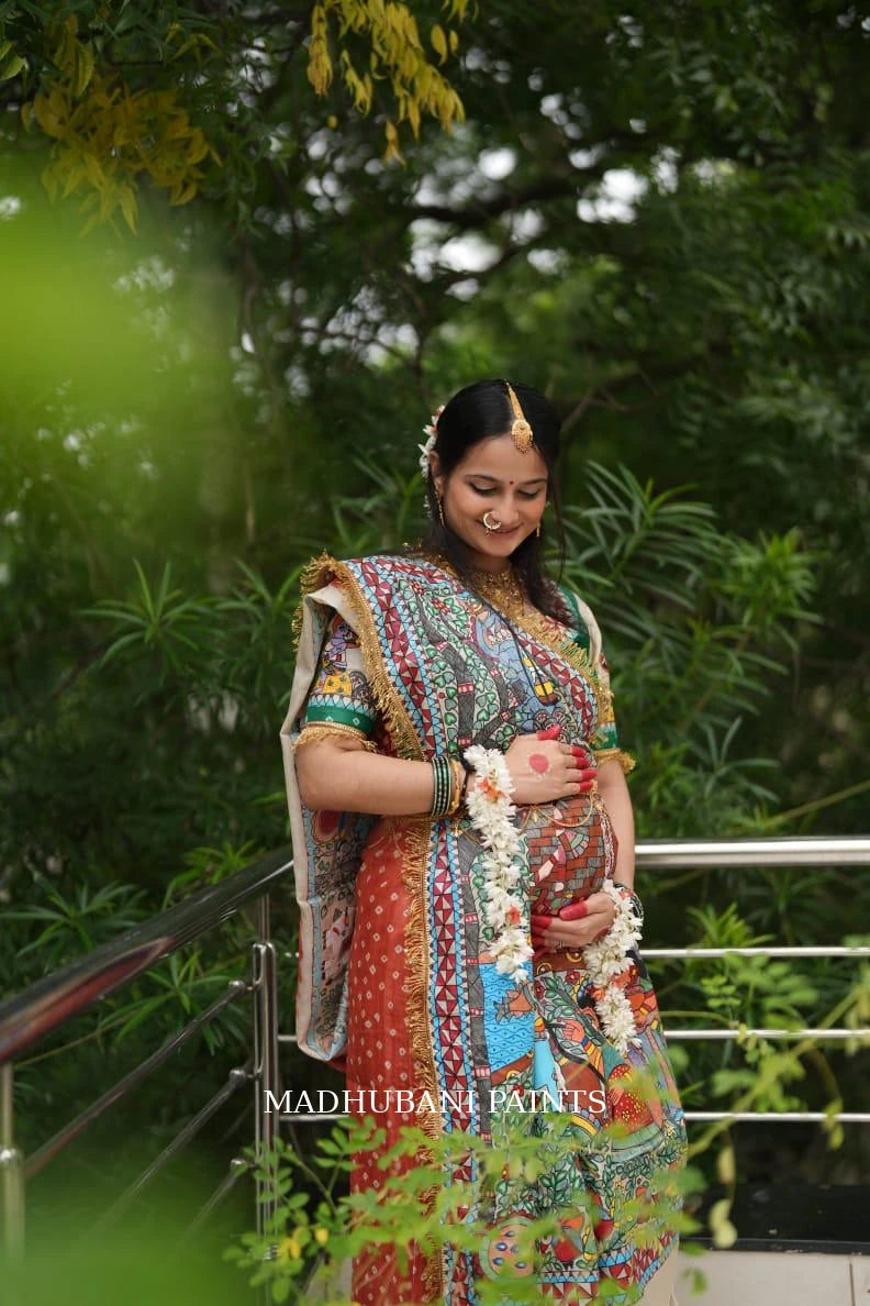 Expectant mother wearing a colorful hand-painted Madhubani Godh Bharai saree, celebrating motherhood with traditional floral jewelry
