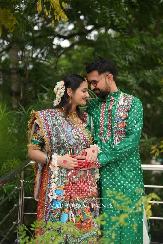 Couple celebrating their Godh Bharai ceremony in traditional outfits featuring a hand-painted Madhubani saree and green kurta