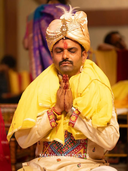 Indian groom dressed in a beige Tussar silk hand-painted Madhubani kurta with traditional Mithila motifs, celebrating wedding rituals.