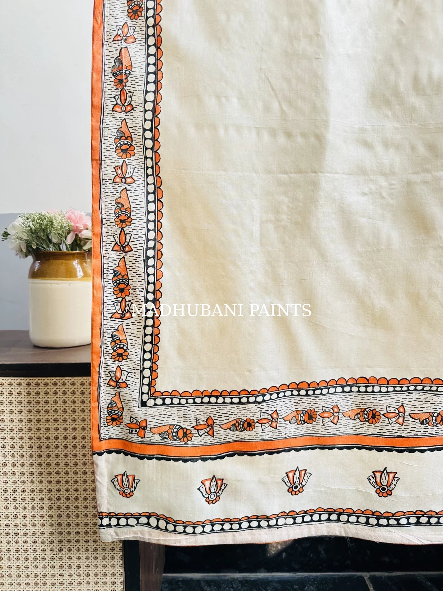 Beige silk stole featuring black and orange coloured hand-painted Lotus and saankh motifs and intricate Madhubani-style borders, handcrafted in traditional Mithila painting art.