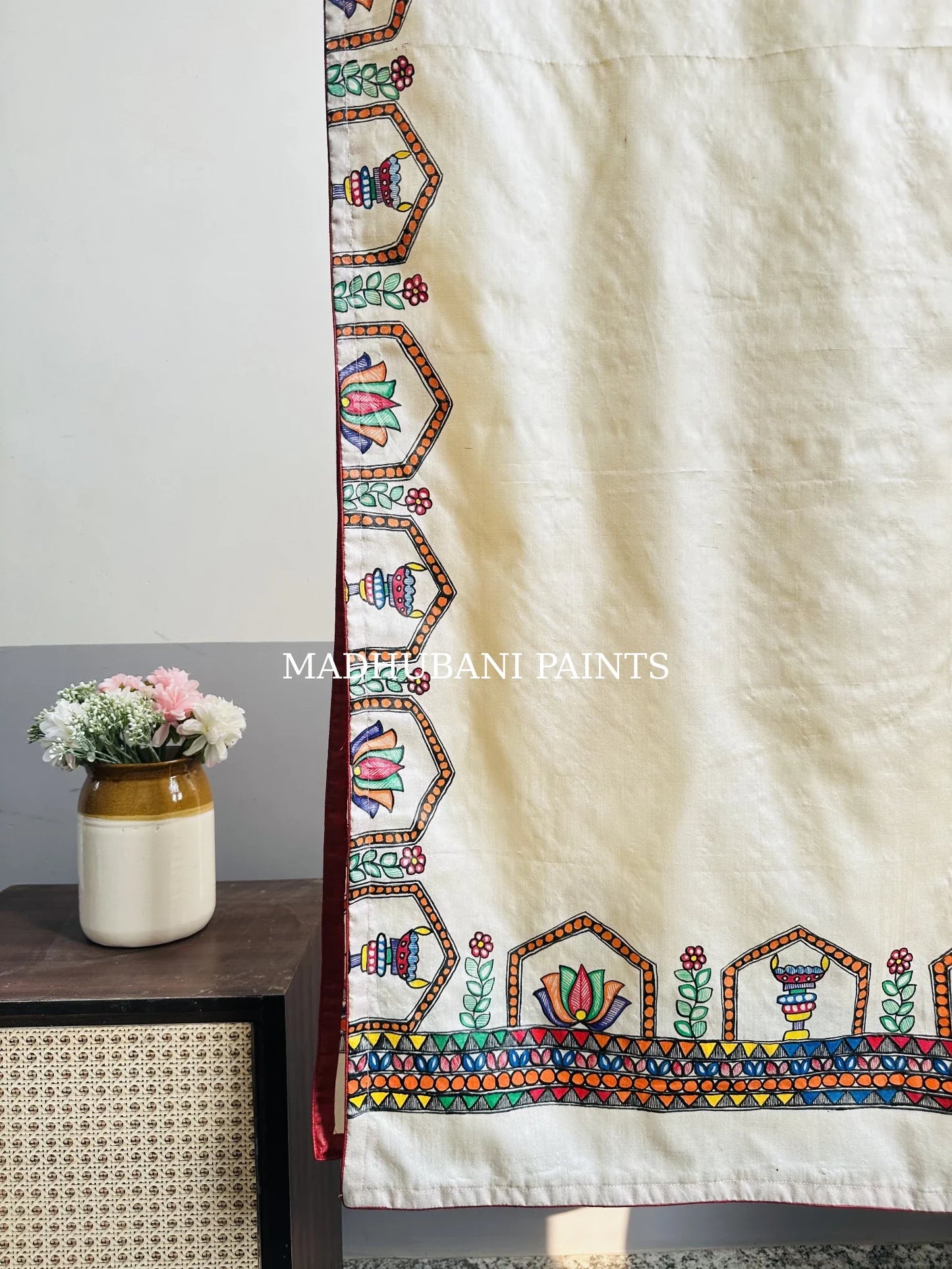 A beige silk stole with colorful hand-painted lotus and diya borders in madhubani painting art