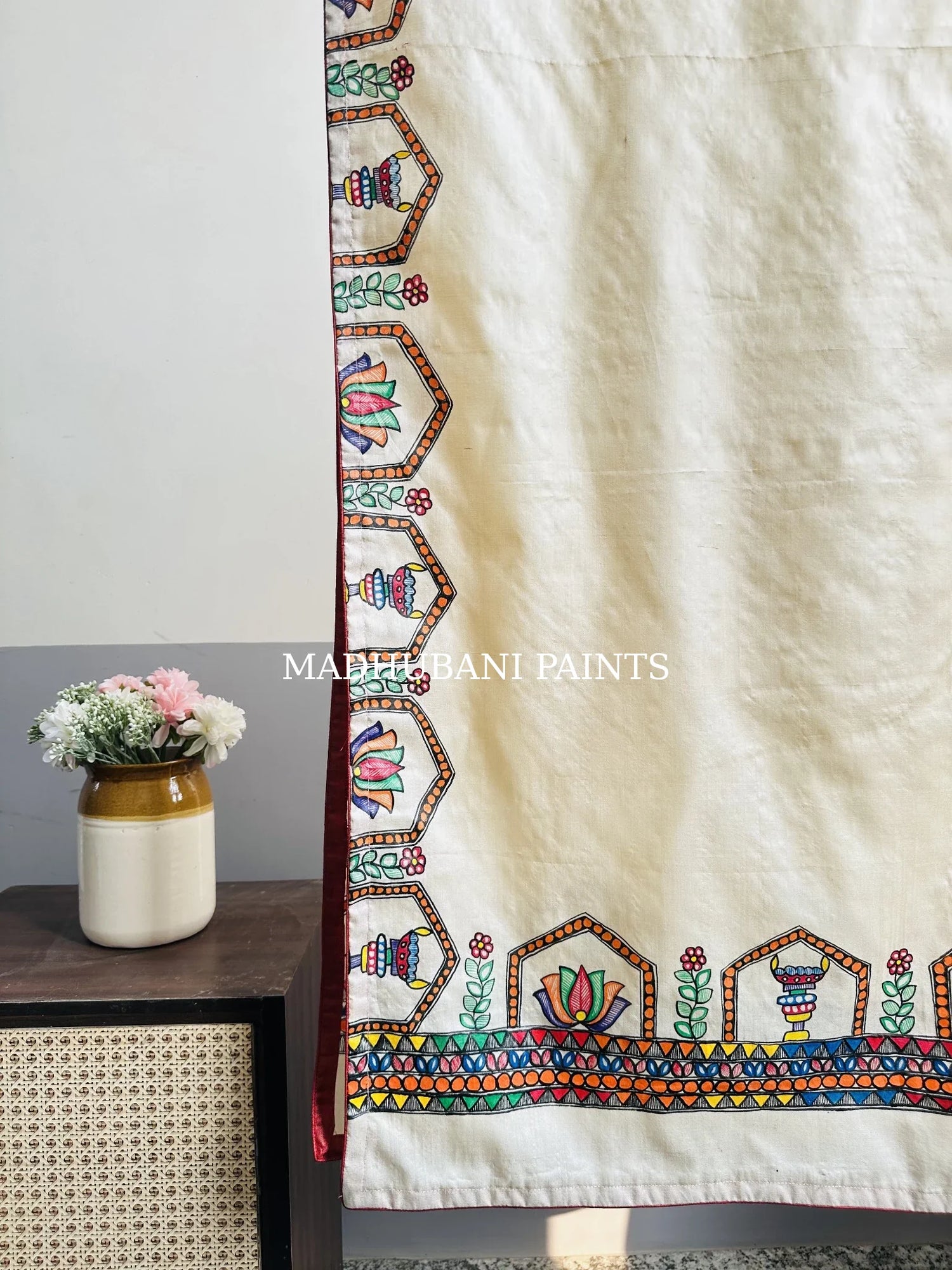 A beige silk stole with colorful hand-painted lotus and diya borders in madhubani painting art