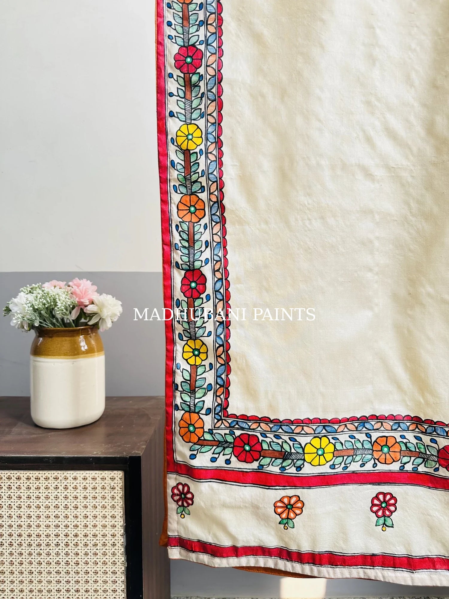 A beige silk stole with colorful hand-painted flower and madhubani borders in madhubani painting art