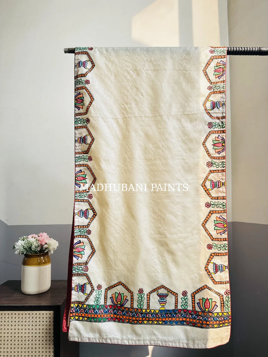A beige silk stole with colorful hand-painted lotus and diya borders in madhubani painting art