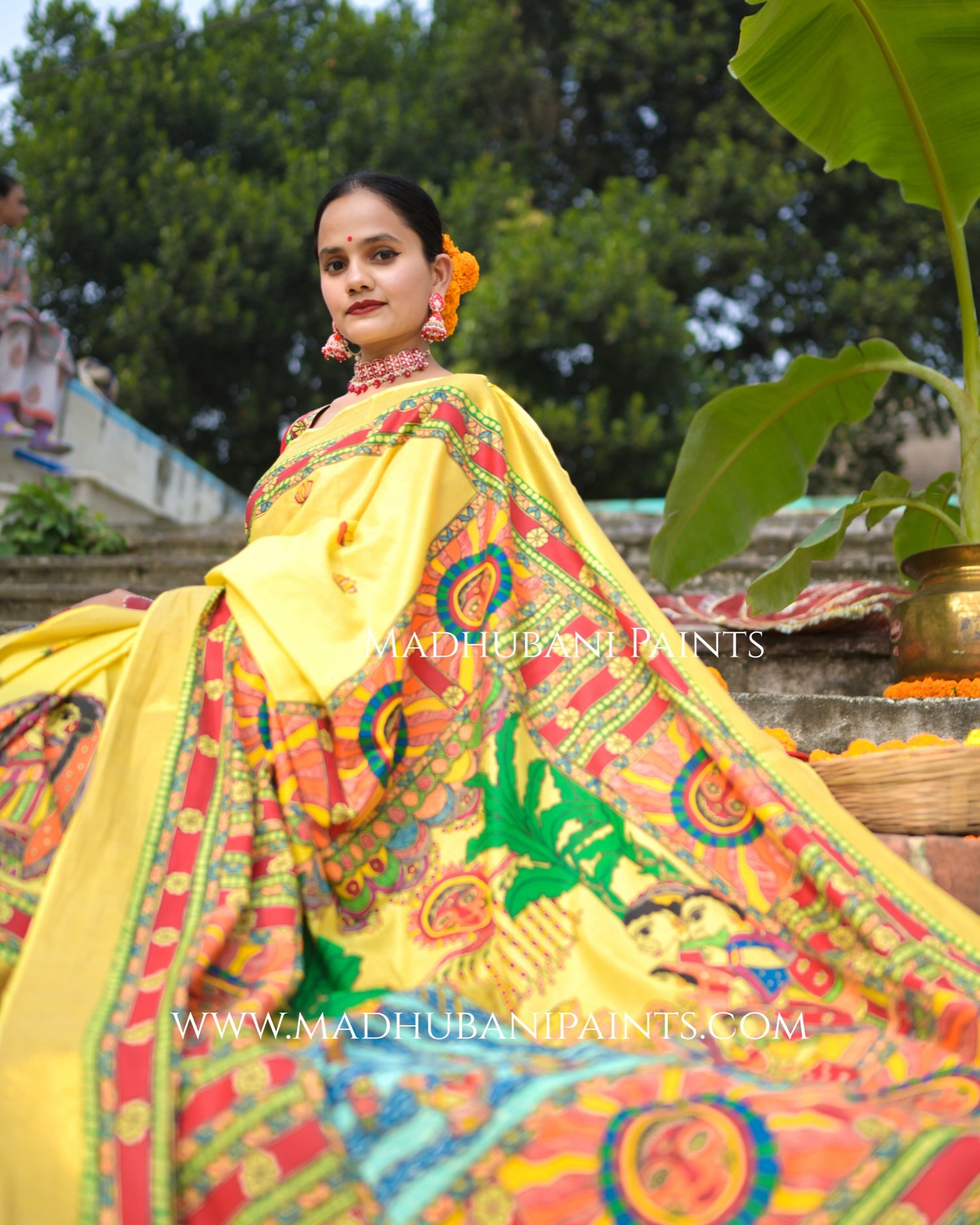 Woman wearing a colorful saree with Madhubani Paints branding in an outdoor setting.