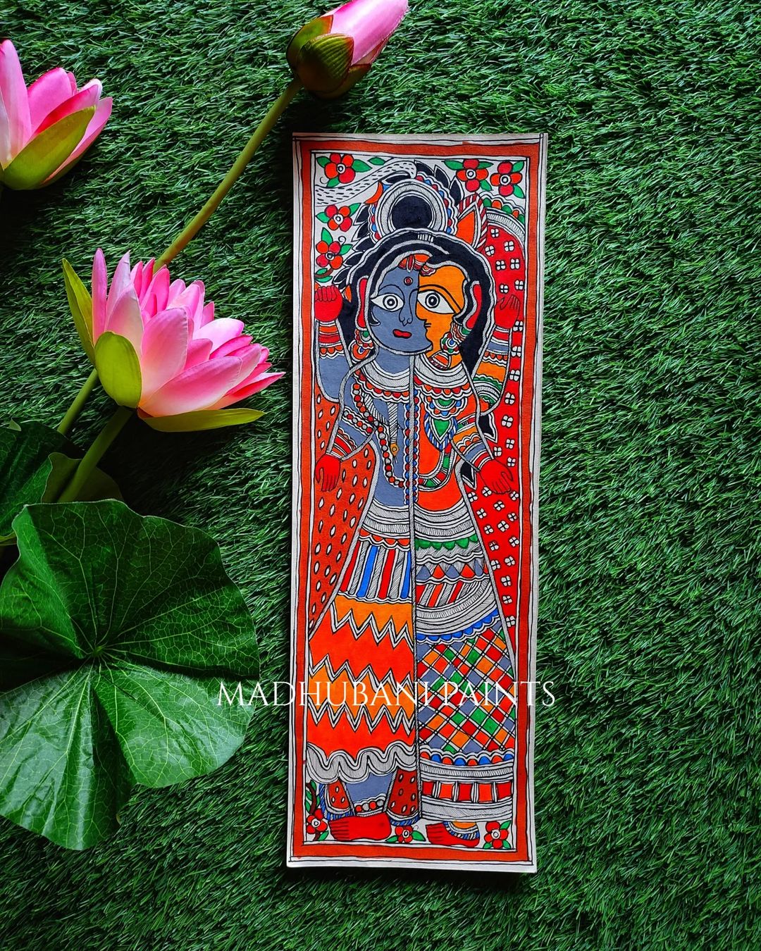 Hand-painted Madhubani painting on paper with a depiction of a goddess, surrounded by green floral accents and leaves.