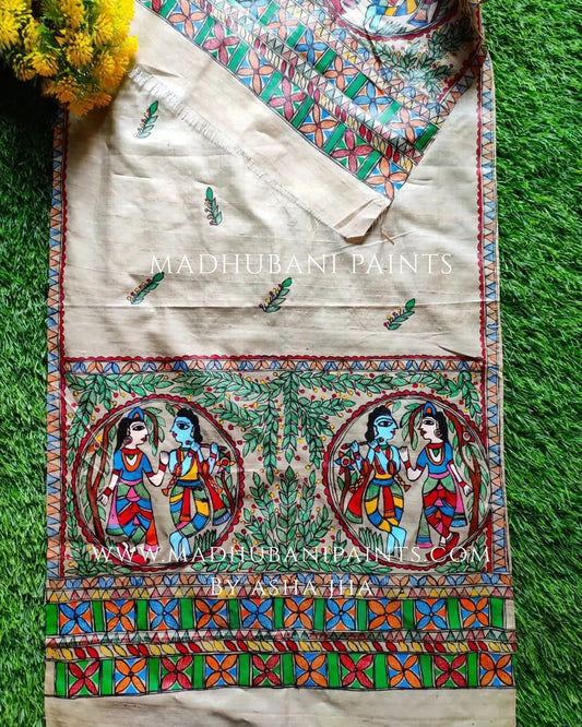 A beige handloom tussar silk stole with a traditional Madhubani artwork depicting Radha and Krishna in the center, surrounded by floral patterns.